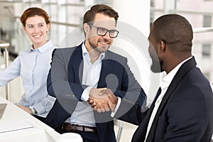 Smiling white man handshaking african american businessman at meeting.