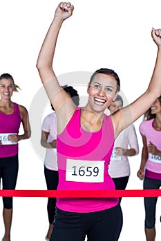 Smiling winner athlete crossing finish line with arms raised