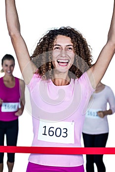 Smiling winner female athlete crossing finish line with arms raised
