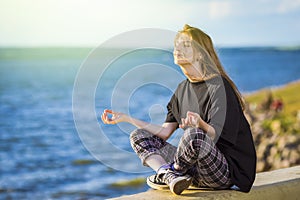 Smiling Winsome Relaxing Caucasian Blond Female Girl Posing With Folded Legs Outdoors While Sitting And Meditating Outdoors At