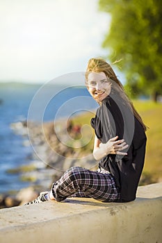 Smiling Winsome Relaxing Caucasian Blond Female Girl Posing Outdoors While Sitting With Positive Facial Expression Outdoors At