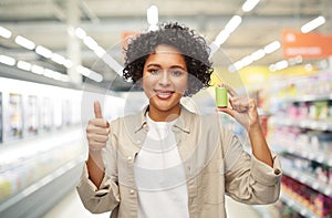 smiling woman with alkaline battery at supermarket