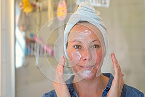 Smiling woman applying moisturiser to her face