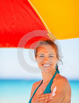 Smiling woman applying sun block creme on arm