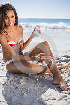 Smiling woman applying sun cream on her leg