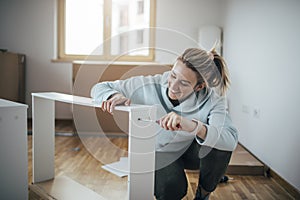 Smiling woman assembling furniture at home