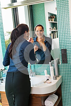 Smiling woman bathroom applying lipstick mirror businesswoman