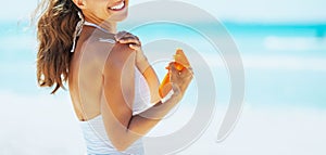 Smiling woman on beach applying sun block creme