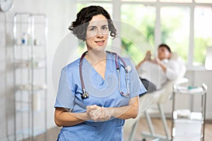 Woman beautician wearing blue overall posing in clinic of esthetic medicine photo