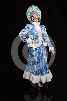Smiling woman in a beautiful suit of the Russian snow maiden. New Year mood. Black background.
