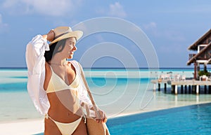 smiling woman in bikini and hat on exotic beach