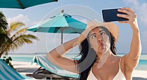 smiling woman in bikini taking selfie on beach