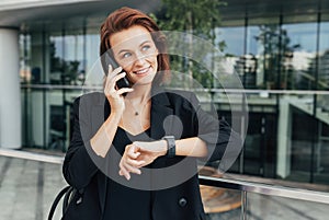 Smiling woman in black formal wear sets a time for a meeting