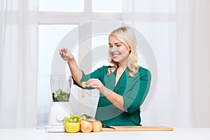 Smiling woman with blender cooking food at home