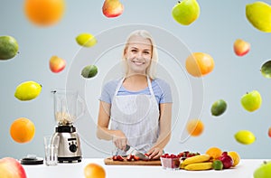 Smiling woman with blender preparing fruit shake