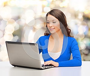 Smiling woman in blue clothes with laptop computer