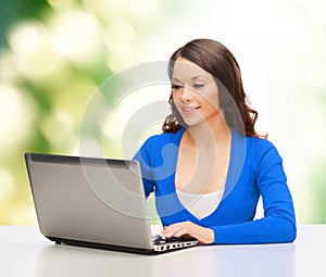 Smiling woman in blue clothes with laptop computer