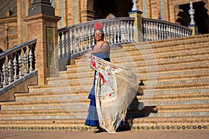 The smiling woman with the blue flamenco dress in Plaza de Espana mimics the torero`s movement photo