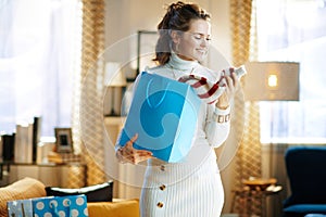 Smiling woman with blue shopping bag checking purchased sweater