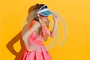 Smiling Woman In Blue Sun Visor On Yellow Background