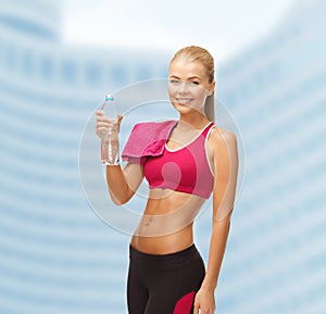 Smiling woman with bottle of water and towel