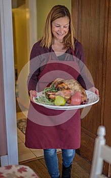 Woman carrying turkey on platter for Thanksgiving meal