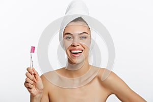 Smiling woman brushing her teeth with towel on her head. A great smile