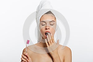 Smiling woman brushing her teeth with towel on her head. A great smile