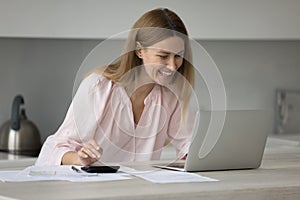 Smiling woman calculates incomes, expenses on calculator pay bills online