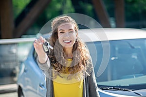 Smiling woman with car key in outstretched hand