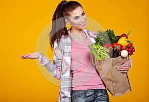 Smiling woman carrying a bag with vegetables