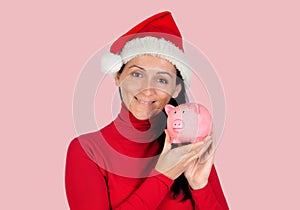 Smiling woman with christmas hat and a piggy-bank