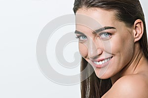 Smiling woman with clean skin, natural make-up, blue eyes, long straight healthy hair and white teeth on white background.