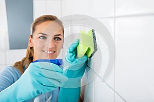 Smiling Woman Cleaning The White Tiled Wall