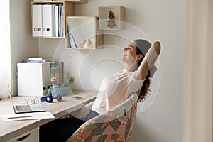 Smiling woman with closed eyes leaning back in office chair