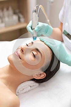 Smiling woman closing her eye during the dermabrasion procedure photo