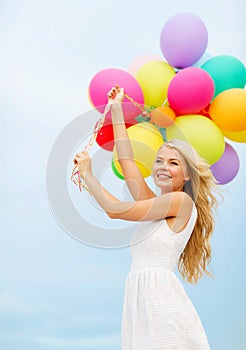 Smiling woman with colorful balloons outside