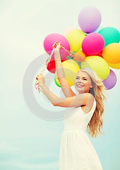 Smiling woman with colorful balloons outside