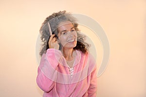 Smiling woman combing hair Graying hair Bathrobe