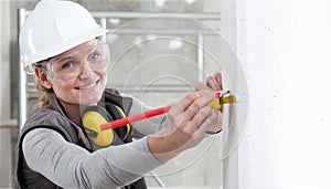 Mujer sonriente construcción obrero cinta a lápiz medidas muro en el edificio paginas agotador casco anteojos 