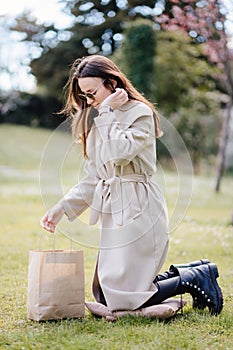 smiling woman consumer holding craft bag present in park