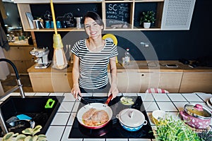 Donna sorridente cucinando salutare pasto la cucina. creazione sul la cucina isola piedi secondo piano cottura. preparazione 