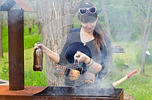 Smiling woman cooking outdoors over a BBQ