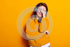 Smiling woman covering face and listening to music on headphones