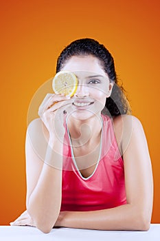 Smiling woman covering her one eye with orange