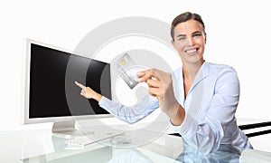 smiling woman with credit card in office at desk front of computer pointing at screen