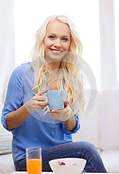 Smiling woman with cup of tea having breakfast