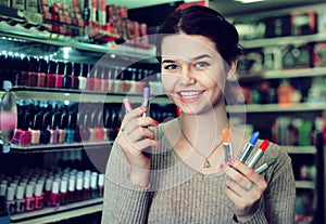 Smiling woman customer browsing rows of lipstick