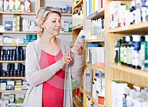 Smiling woman customer browsing rows of skin care products