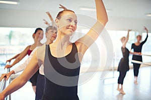 Smiling woman dancing ballet and looking away in class